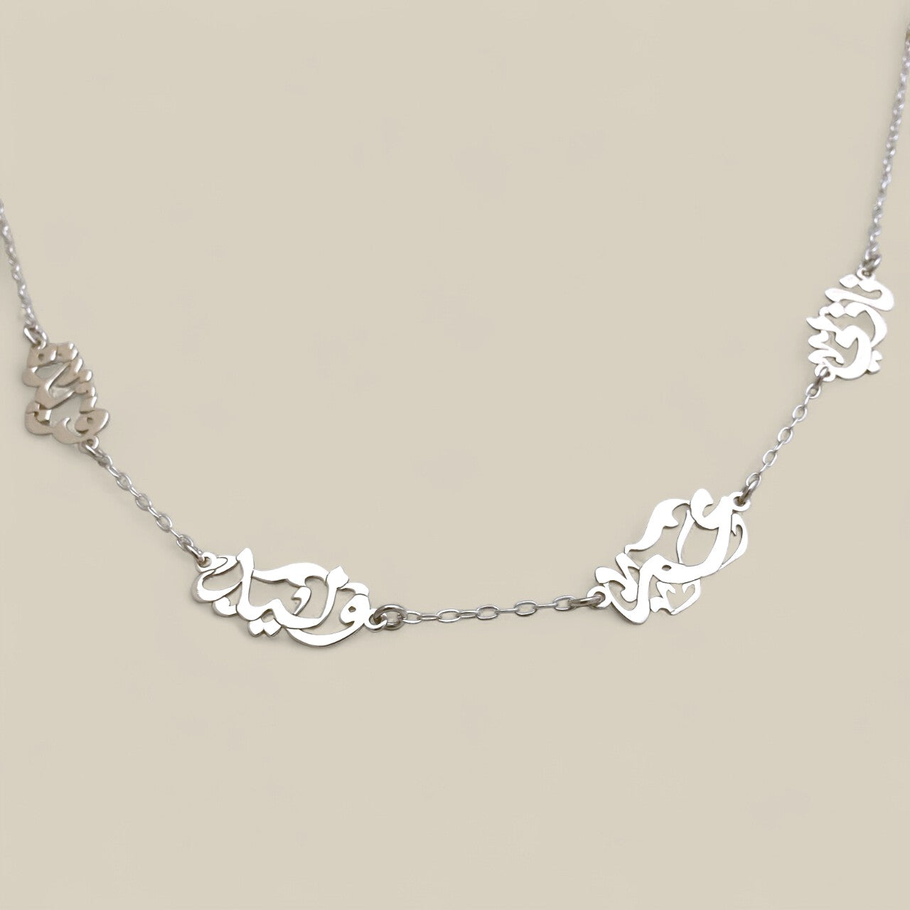 Silver necklace with intricate designs on a beige background