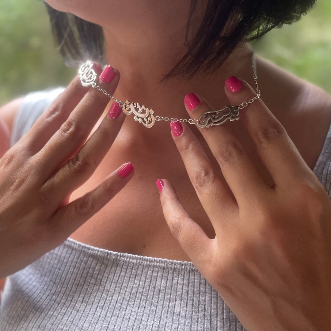Close-up of a person wearing a gold necklace with intricate designs, with hands adjusting it.