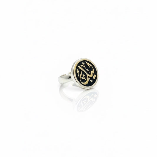 Silver ring with black and gold Arabic calligraphy on a white background