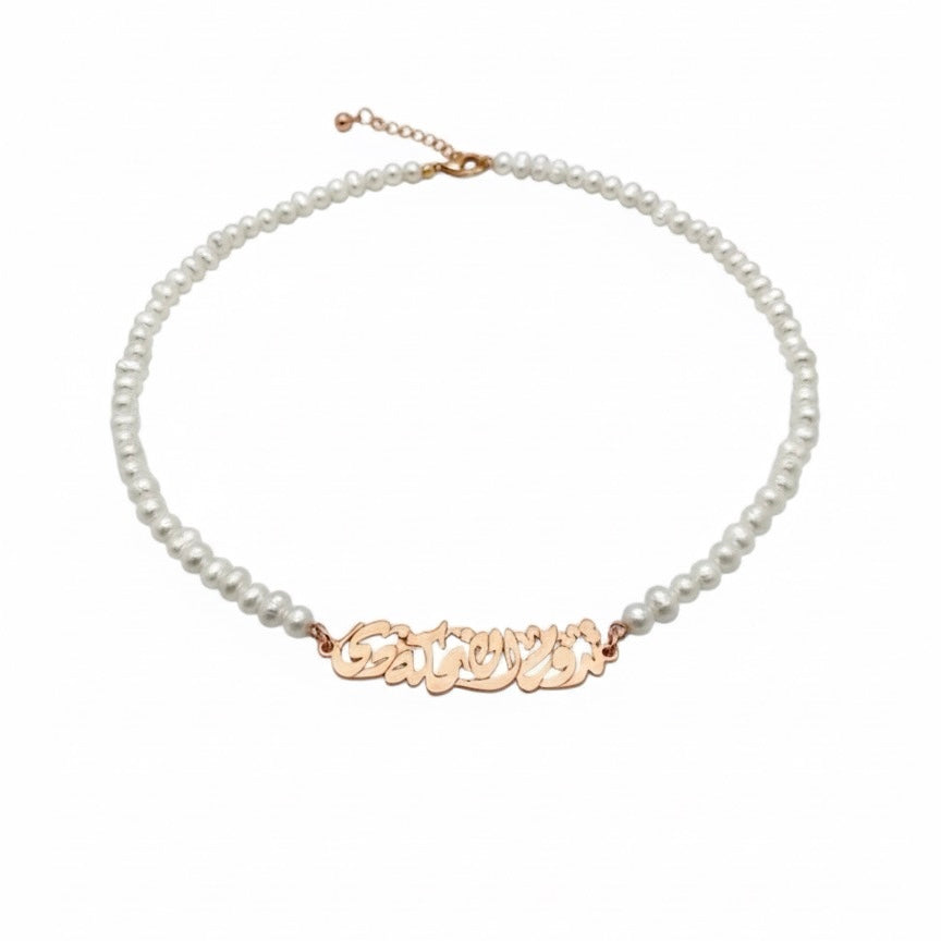 Pearl necklace with a gold nameplate on a white background